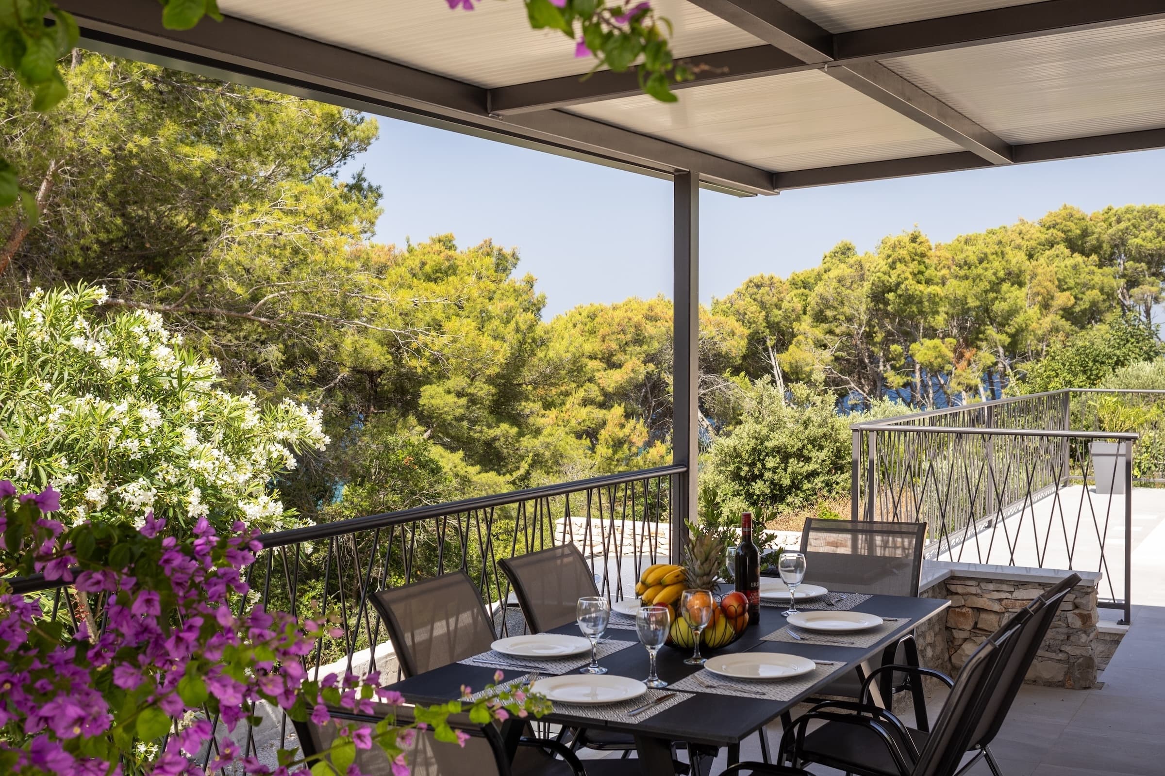 Überdachte Terrasse mit mediterranem Grün und Blick Richtung Meer
